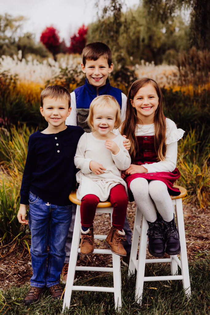 Close-up of Roe family grandchildren sitting together on stools in Sheboygan, WI during fall family photo session