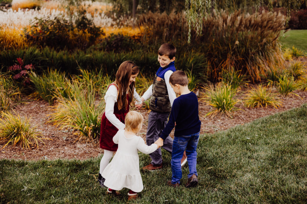 Roe family cousins holding hands and playing Ring Around the Rosie during fall family photo session in Sheboygan, WI.