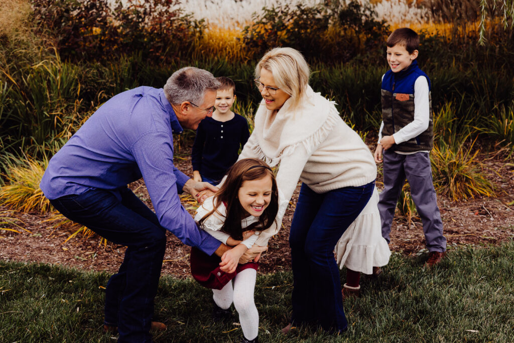 Grandparents tickling granddaughter as cousins laugh in the background during candid fall family session in Sheboygan, WI.