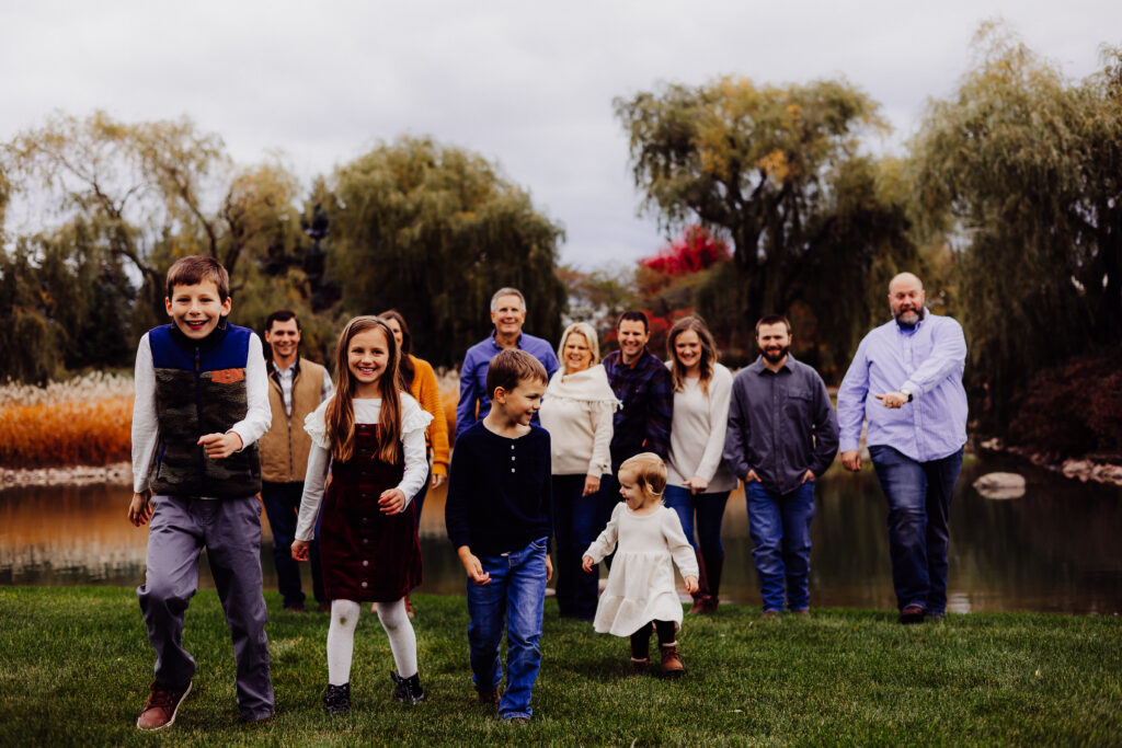 Roe family walking together during fall photo session in Sheboygan, Wisconsin with children leading and adults smiling behind them.
