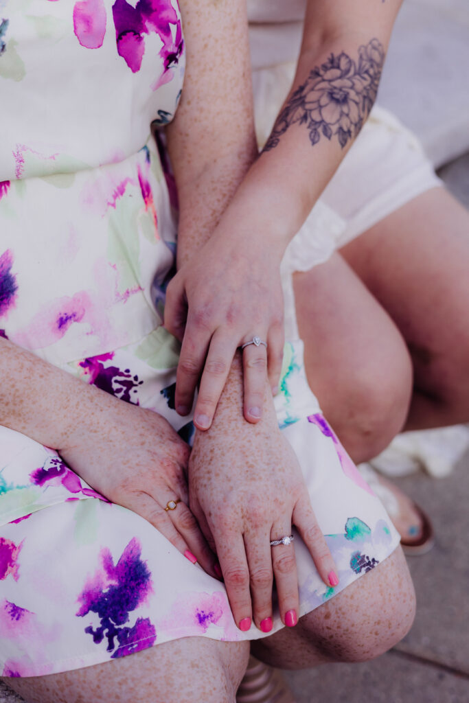 Close-up of Lauren and Carley’s hands showing matching engagement rings during their spring engagement session at the Wisconsin State Capitol in Madison, WI.