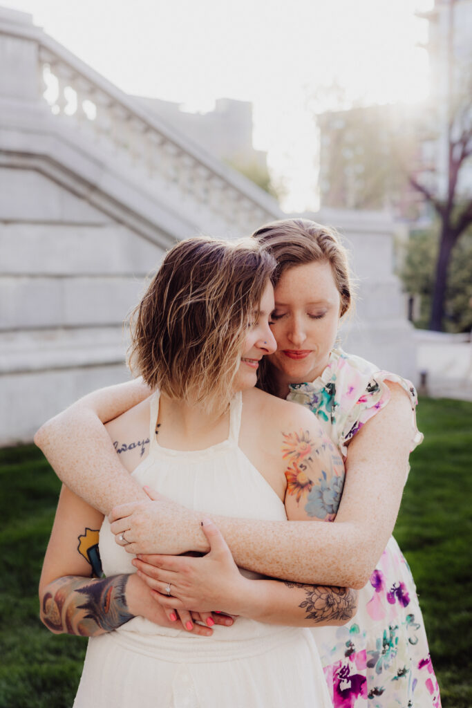 Carley hugging Lauren from behind with soft golden spring light at the Wisconsin State Capitol in Madison, WI.