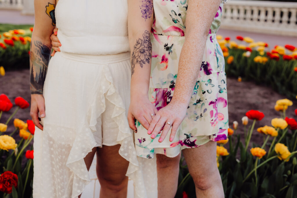 Close-up of Lauren and Carley’s hands showing matching engagement rings during their spring engagement session at the Wisconsin State Capitol in Madison, WI.