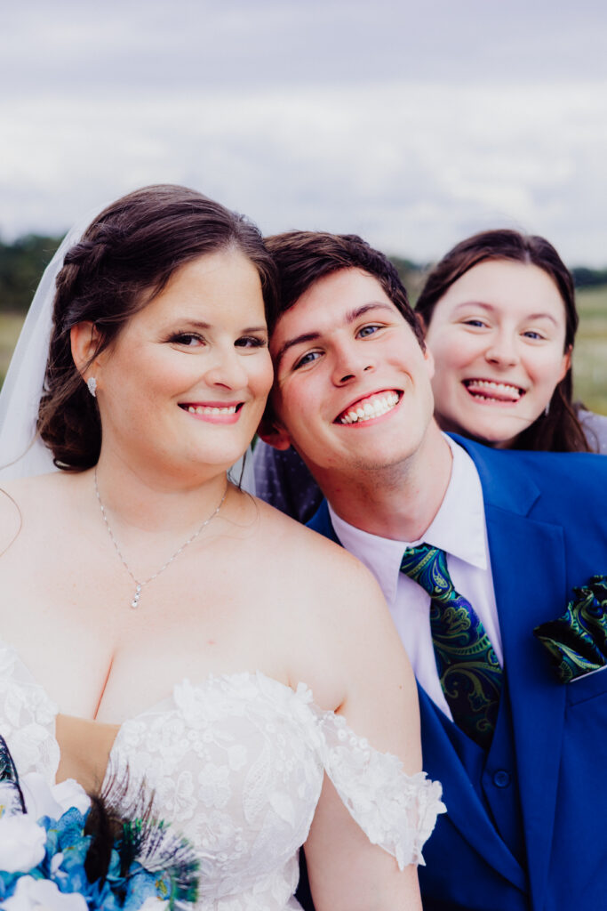 Bride smiles with two family members leaning in close for a fun, candid wedding day photo outdoors in Wisconsin.