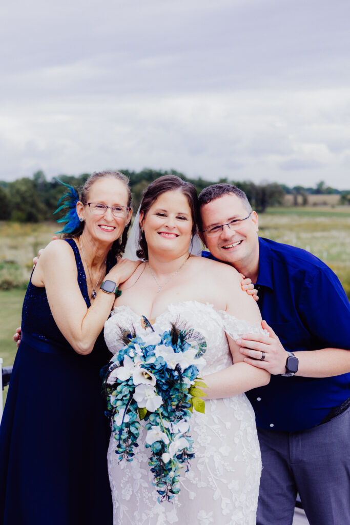 Bride smiles with two family members leaning in close for a fun, candid wedding day photo outdoors in Wisconsin.